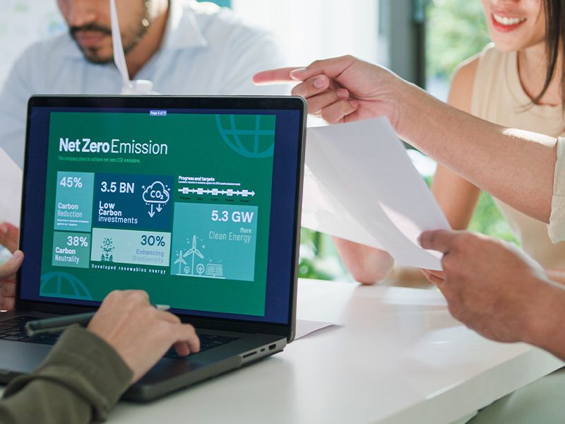 Team reviewing Net Zero data on a laptop screen, showing how basket energy procurement supports carbon reduction, cost savings, and sustainability goals.
