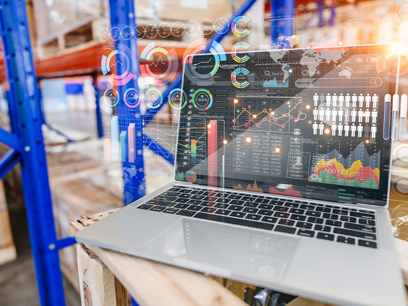 Laptop displaying digital dashboards and analytics in a warehouse, representing the benefits of AMR energy meters and BMS audits for data-driven decisions.