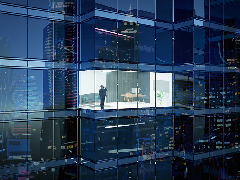 Modern glass office building at night with a lit interior office, symbolising real-world case studies of AMR energy meters and BMS audits in action.
