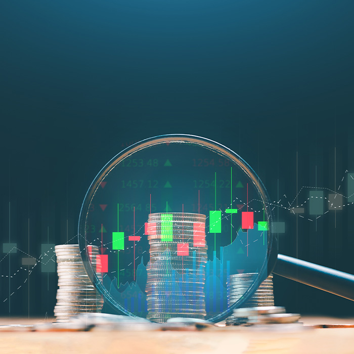 Coins and data graphs under a magnifying glass symbolising cost analysis during an Energy audit.