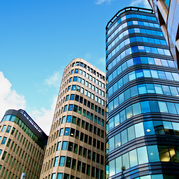 Cluster of modern office buildings with glass façades, representing the importance of a track and trace survey for commercial buildings to manage utilities and compliance.