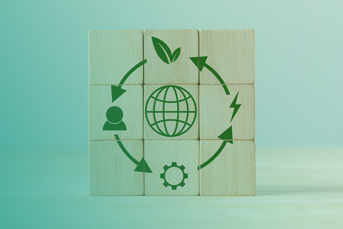 Wooden blocks arranged in a square with green icons showing a circular ecology cycle, representing the principles of a Sustainability Life Cycle Assessment.