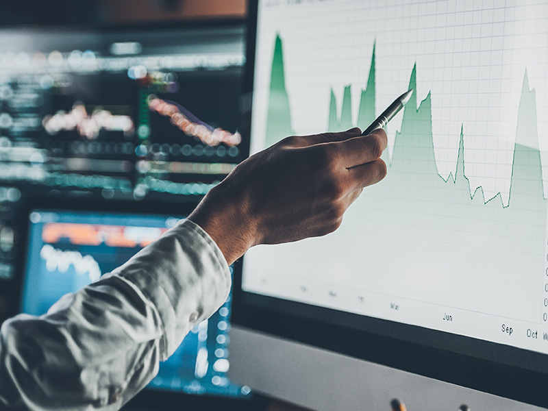 Hand pointing at a digital chart on a monitor, symbolising how energy market intelligence for procurement supports forecasting and risk management.
