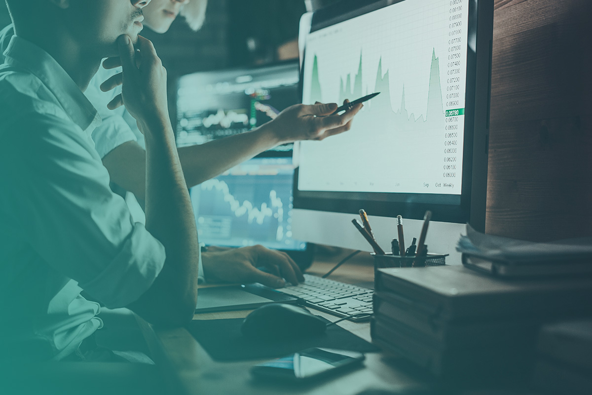 “Energy analysts reviewing live market charts on a computer screen, illustrating how Energy market intelligence for procurement supports informed buying decisions.”