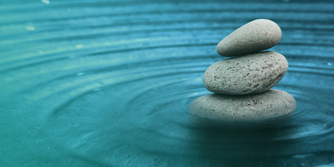 Stacked stones creating balance in calm water, symbolising simplicity, stability, and balance in developing a fixed energy procurement strategy 2025.