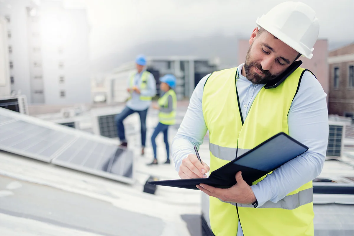 Engineer conducting infrastructure checks while discussing project details during a siteworks discovery call on a rooftop with solar panels.