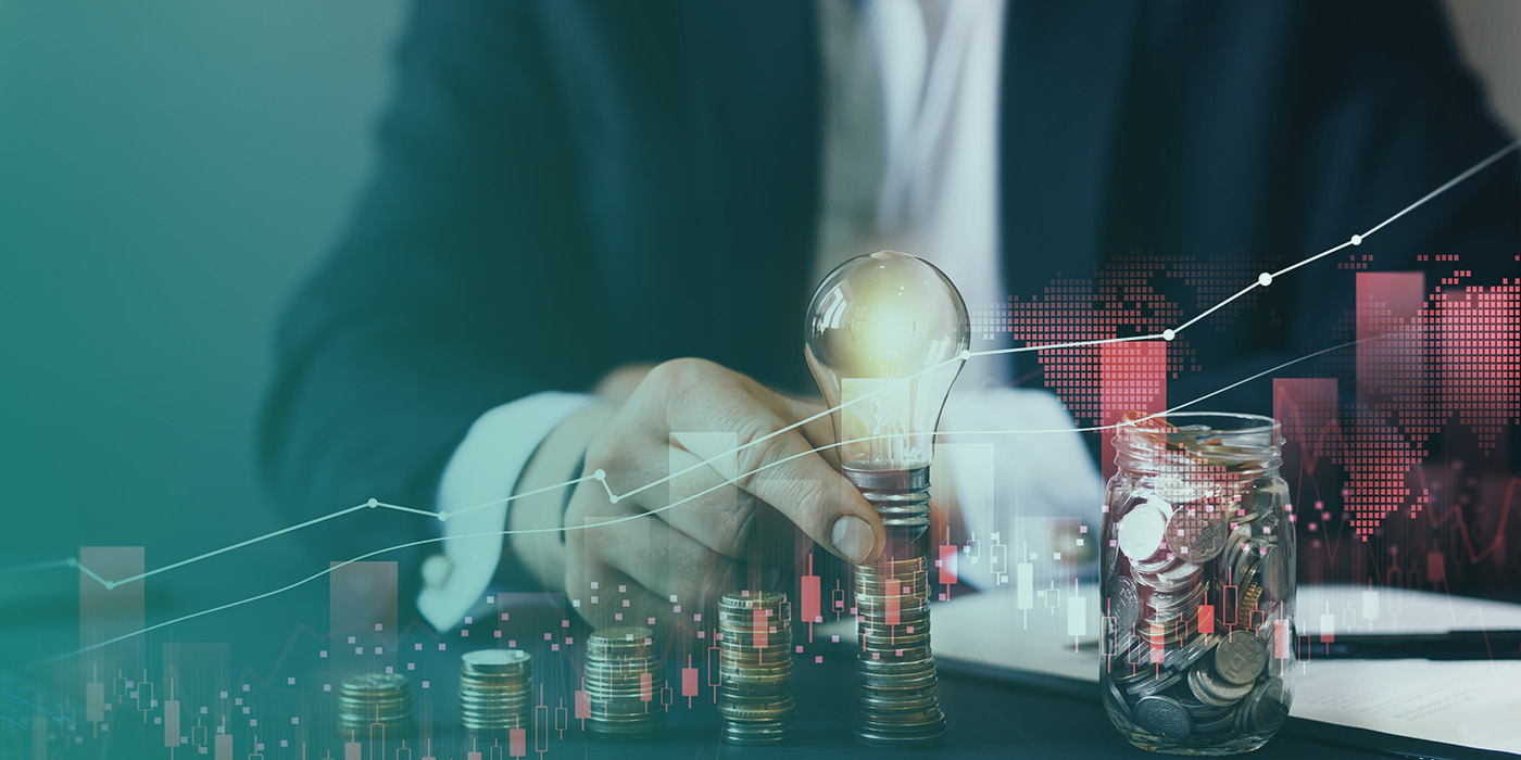 Close-up of a businessperson stacking coins beside a glowing lightbulb, symbolising rising energy costs and the importance of Energy Risk Management 2026.