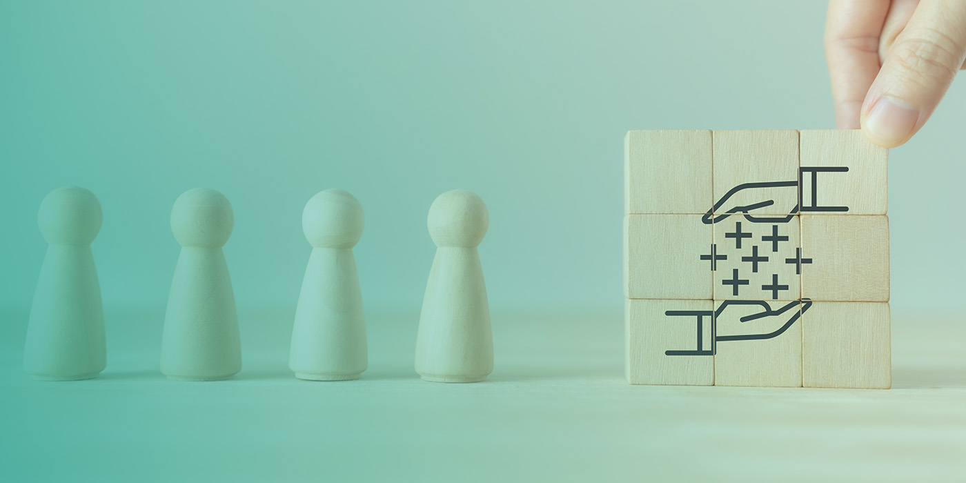 Hand arranging wooden blocks with an icon representing added value, next to wooden figures, symbolising how managing MOP DC DA AMR Contracts improves control and clarity.