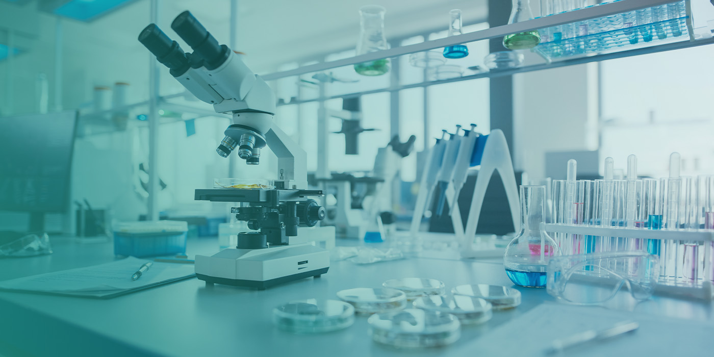 Laboratory workspace with microscopes, test tubes, and scientific equipment, highlighting how BMS Optimisation supports precise environmental control in science parks and laboratories.