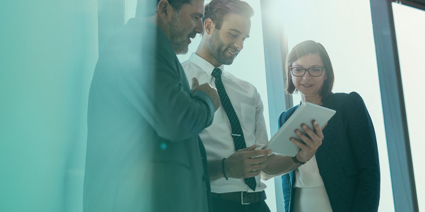 Three professionals reviewing information on a tablet as they discuss key actions from a BMS Optimisation Checklist.