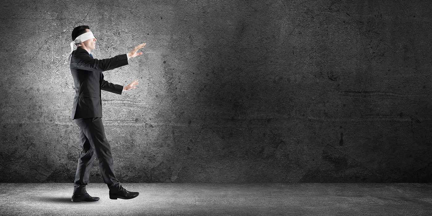 Blindfolded business professional walking forward, representing the visibility gap that occurs when AMR and site works for portfolio energy strategy are missing or misaligned.